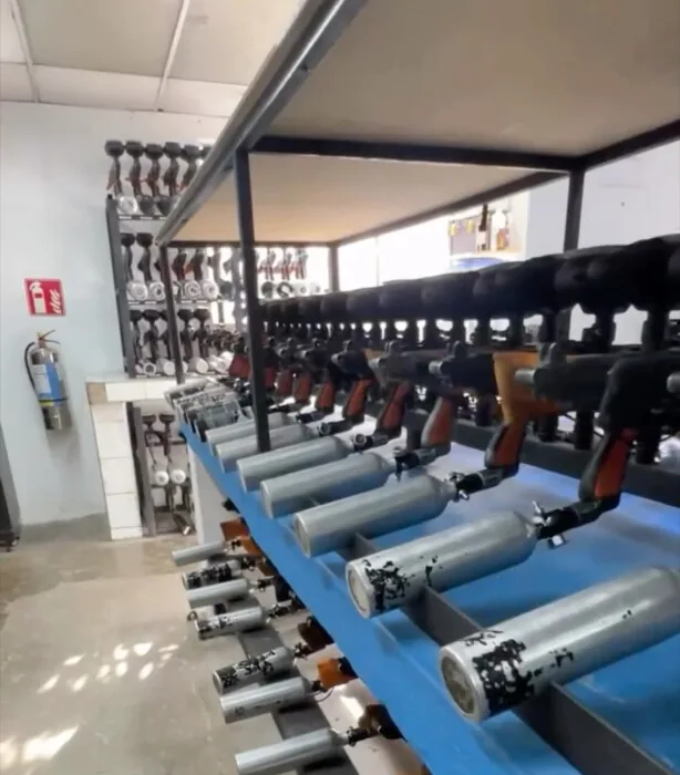 Armería de la sede Quito: estanterías con decenas de marcadoras alineadas y filas de tanques de aire